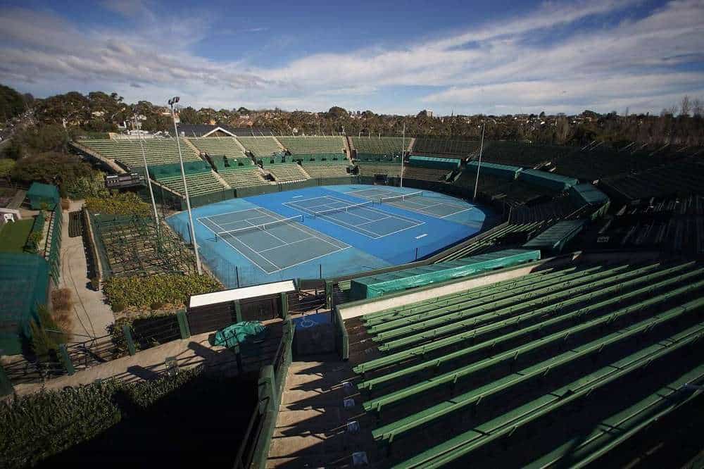 The centre court and green grandstand seating at Kooyong Stadium in Melbourne under a blue sky